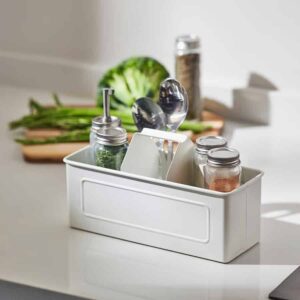 Jars and utensils organized in a white storage box on a kitchen countertop.