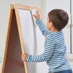 Child erasing chalkboard with cloth in classroom or home setting.