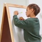 Child writing on whiteboard, online shopping concept, educational tools, and children’s learning products.