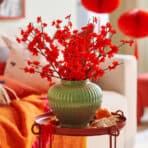 Beautiful red flower arrangement in a green vase. Perfect for home decor, creating vibrant and festive ambiance.