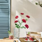 Vase with vibrant red flowers on a cozy table, perfect for home decoration and online shopping at OKDEALS.