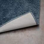 High-quality blue plush rug with a durable beige backing for home comfort. Perfect for living rooms or bedrooms.