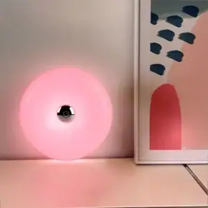 Pink LED decorative lamp with abstract artwork in the background.
