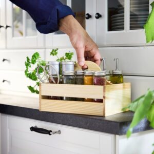 Wooden spice rack with jars on kitchen countertop.