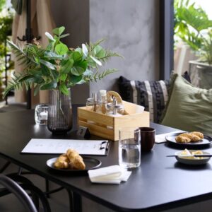 Contemporary dining table with flowers, drinks, and snacks in a cozy setting.