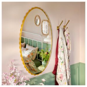 Decorative oval mirror with yellow frame in a cozy bedroom setting.