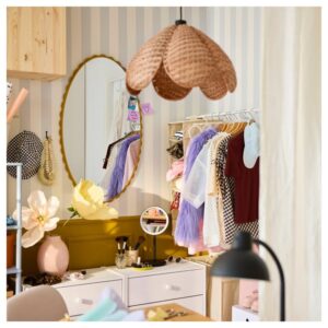 Dark yellow DAGGKAPRIFOL mirror with clothing rack and decor in bedroom.