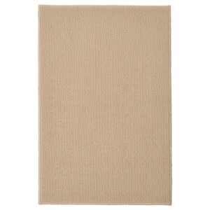 Beige bath mat with textured surface for bathroom decor.