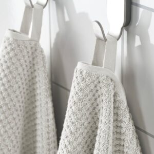 White GULVIAL hand towels hanging on hooks in a bathroom.