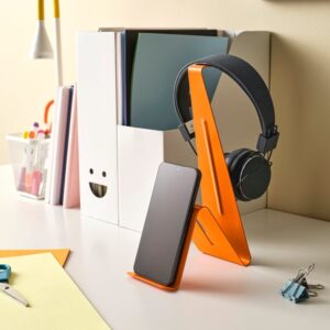 Orange headset and tablet stand on a white desk with books and stationery.