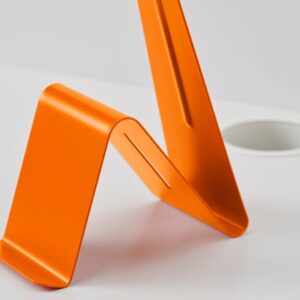 Orange headset and tablet stand for ergonomic workspace setup.