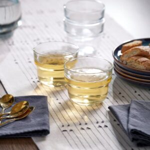 Clear glass cups with tea on a dining table with snacks and cutlery.