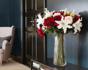 Beautiful artificial flower arrangement with white lilies and red roses in a glass vase.