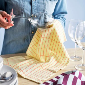 Person pouring wine with patterned tea towel on table.
