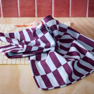 Multicolour checkered tea towel draped on wooden surface.