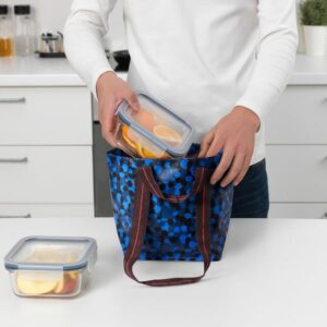 Person packing food into a blue patterned reusable carrier bag in kitchen.