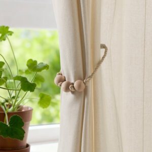 Beige magnetic curtain tie-back holding curtains open in a bright room.