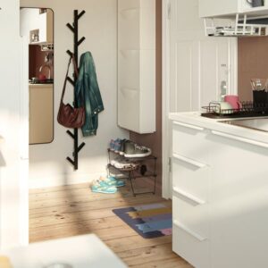 Modern indoor entryway with coat rack, shoes, and a colorful rug.
